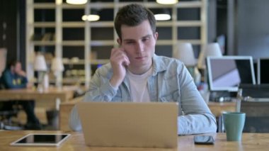 Ciddi Genç Erkek Tasarımcı Düşünüyor ve Laptop üzerinde çalışıyor