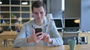 Modern Ofis 'te akıllı telefon kullanan çekici genç tasarımcı