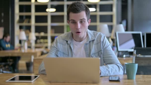 Verrast jonge ontwerper viert succes op laptop in kantoor — Stockvideo