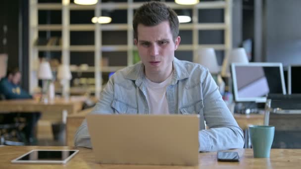 Droevige jonge ontwerper geconfronteerd met verlies op laptop in het moderne kantoor — Stockvideo