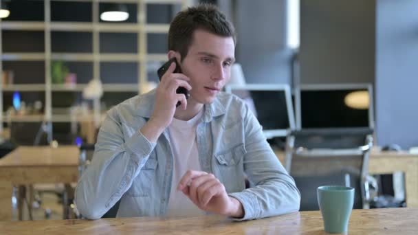 Fröhliche junge Designerin im Büro im Smartphone-Gespräch — Stockvideo