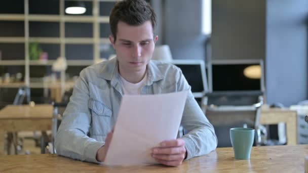 Joven Diseñador Enfocado Escribiendo en Papel en Oficina Moderna — Vídeo de stock