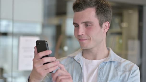 Porträt eines fokussierten jungen männlichen Designers mit Smartphone — Stockvideo