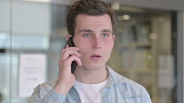 Портрет веселого молодого дизайнера, який розмовляє по смартфонах — стокове відео