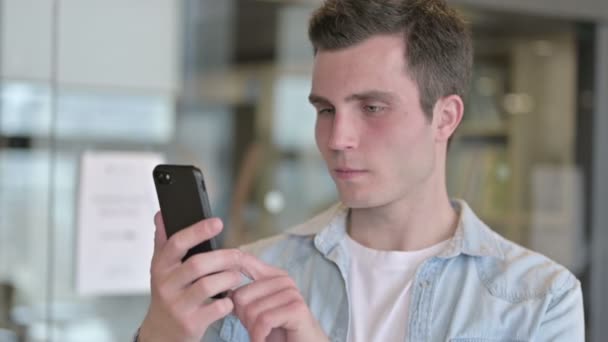 Porträtt av ung designer firar framgång på Smartphone — Stockvideo