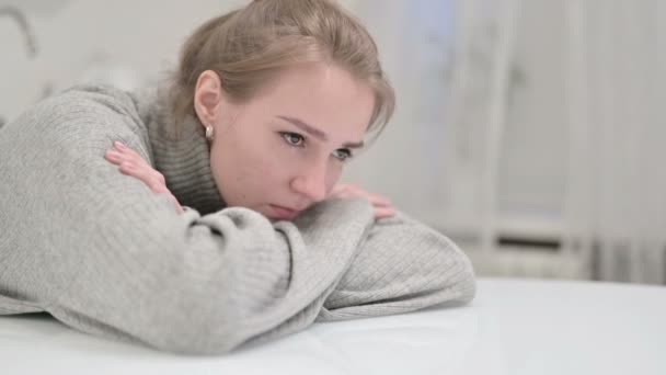 Несчастная молодая женщина отдыхает на столе и думает — стоковое видео