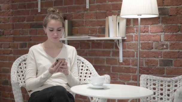 Fröhliche junge Frau trinkt Kaffee und telefoniert — Stockvideo