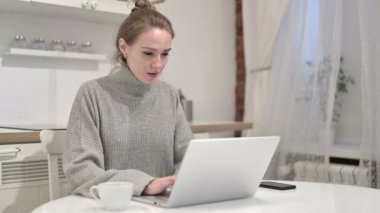 Genç bir kadının kahvesini içip laptopla uğraşması.