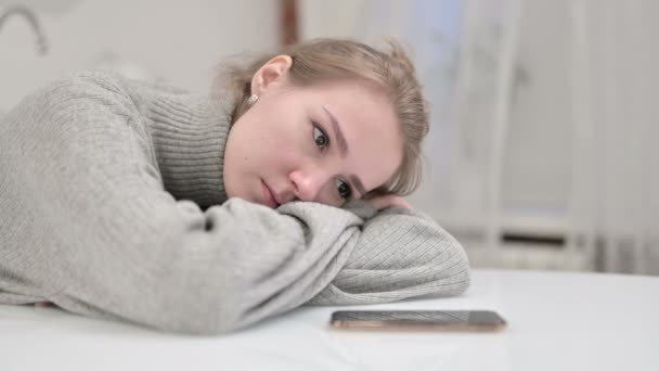 Droevige jonge vrouw rusten op tafel en kijken naar rinkelen Smartphone — Stockvideo