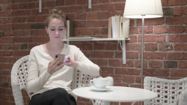 Hermosa mujer joven bebiendo café y usando Smartphone — Vídeo de stock