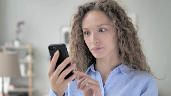 Genç kıvırcık saçlı kadın Akıllı telefon kullanmakla meşgul. — Stok fotoğraf