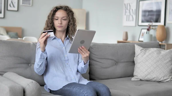 Онлайн-покупки на планшете от кудрявые волосы женщина сидит на диване — стоковое фото