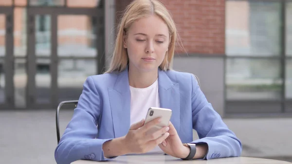 Jovem empresária usando Smartphone sentado ao ar livre — Fotografia de Stock