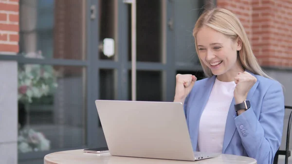 Молодая предпринимательница празднует на ноутбуке сидя вне офиса — стоковое фото