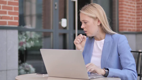 Молодая предпринимательница кашляет во время работы над ноутбуком на открытом воздухе — стоковое фото
