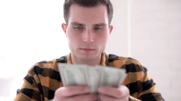 Gespannen jonge man tellen dollar papier valuta — Stockfoto