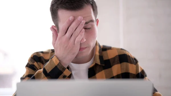 Zbliżenie młodego mężczyzny z bólem głowy praca na laptopie — Zdjęcie stockowe