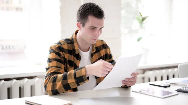 Pensive casual młody człowiek czytanie dokumenty — Zdjęcie stockowe