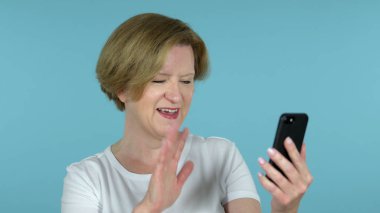 Eski kadın, mavi arkaplan tarafından Smartphone üzerinden online görüntülü sohbet