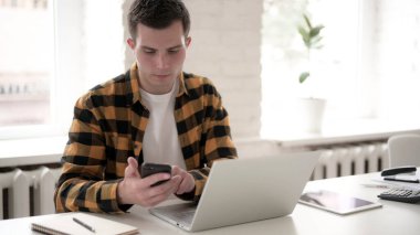 İş yerinde akıllı telefon kullanan sıradan bir genç.