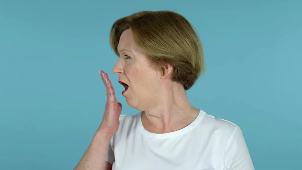 Стара жінка позіхання і розтягування тіла ізольовані на синьому фоні — стокове фото