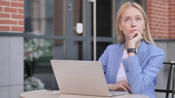 Pensant jeune femme d'affaires assis en plein air — Photo