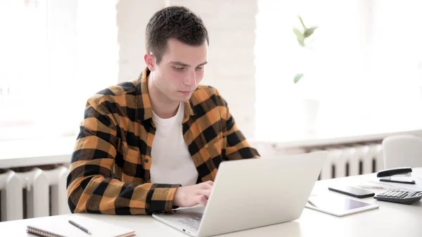 Lässiger junger Mann tippt auf Laptop — Stockfoto