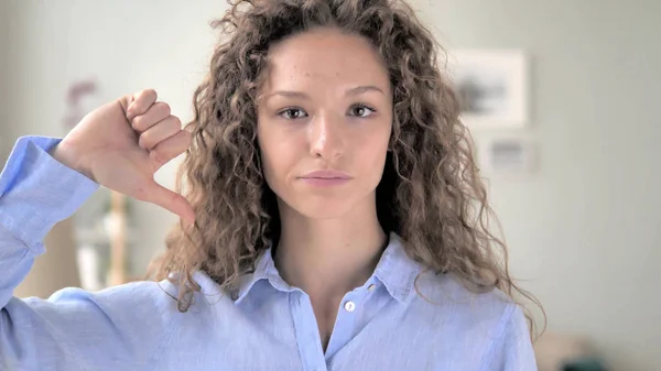 Pouces vers le bas par la femme bouclée de cheveux au travail, regardant la caméra — Photo