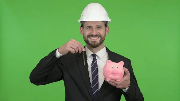De Happy engineer houdt Piggy Bank met huissleutel tegen Chroma Key — Stockfoto