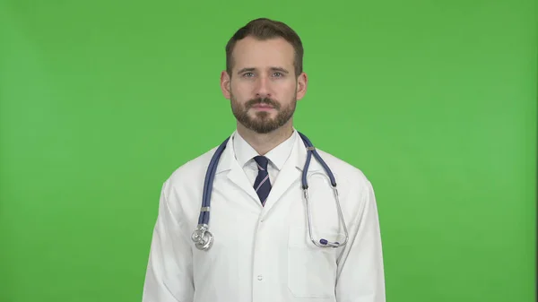 Der gutaussehende Arzt blickt auf Kamera gegen Chromaschlüssel — Stockfoto