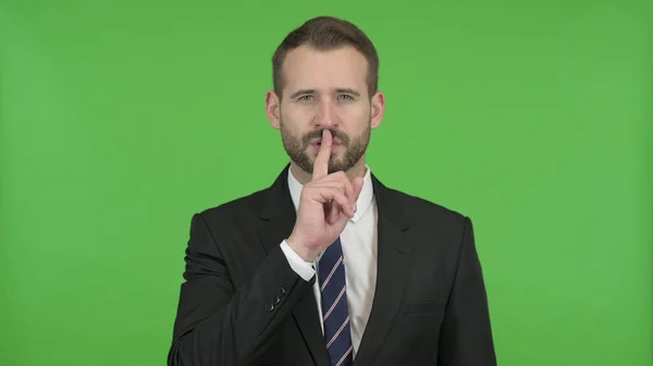 De jonge zakenman zet zijn vinger op de lippen tegen Chroma Key — Stockfoto