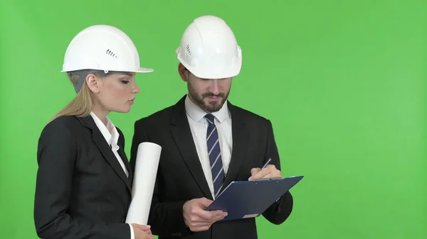 De gelukkige ingenieurs die naar de bouwwerken tegen Chroma Key — Stockfoto