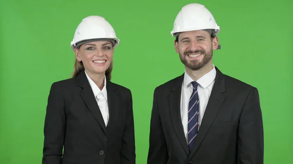 Два інженери з будівництва посміхаються під час дивлячись на камеру від ключ до кольоровості — стокове фото