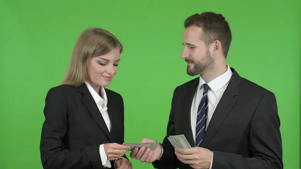 Den manliga professionella ger dollar till kvinnlig professionell mot Chroma Key — Stockfoto