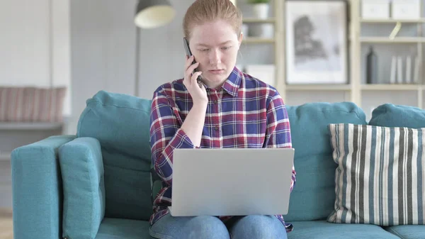 Женщина разговаривает по телефону и работает на ноутбуке — стоковое фото