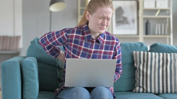 Молодая женщина работает на ноутбуке и с болью в спине — стоковое фото
