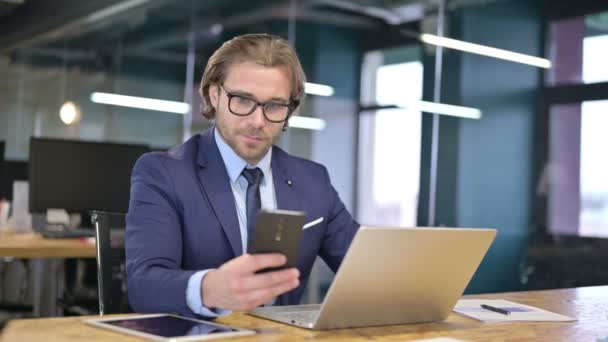 Empresario usando Smartphone y Laptop en la oficina — Vídeo de stock