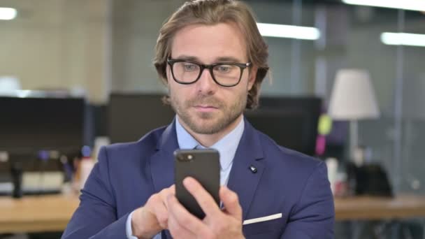 Retrato de empresário usando smartphone no escritório — Vídeo de Stock