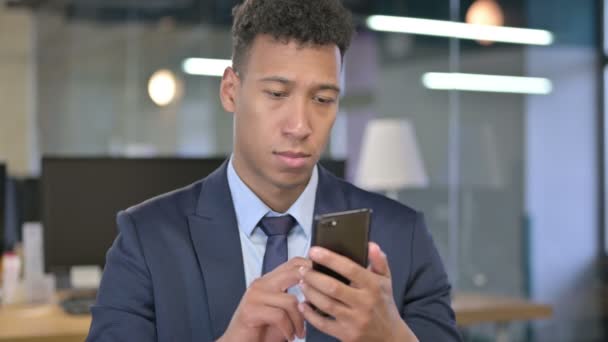 Πορτρέτο του χαρούμενου νεαρού επιχειρηματία χρησιμοποιώντας Smartphone στο γραφείο — Αρχείο Βίντεο