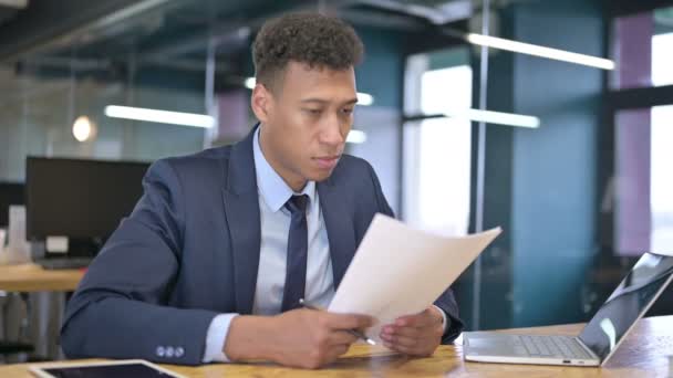 Привлекательный молодой бизнесмен читает документы в офисе — стоковое видео