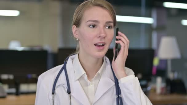 Porträt einer fleißigen jungen Ärztin, die mit dem Smartphone spricht — Stockvideo