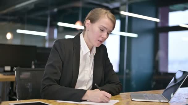 Jovem empresária tentando escrever sobre documentos no escritório — Vídeo de Stock