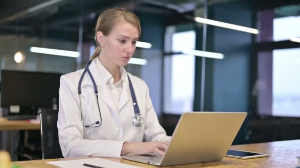 Амбициозная молодая женщина-врач работает над ноутбуком в офисе — стоковое видео
