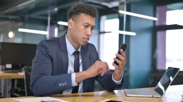 Mladý podnikatel mluví na smartphonu a pracuje na notebooku — Stock video