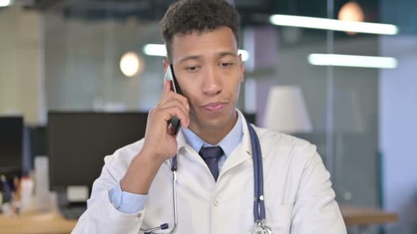 Портрет молодого врача разговаривающего по смартфону в офисе — стоковое видео