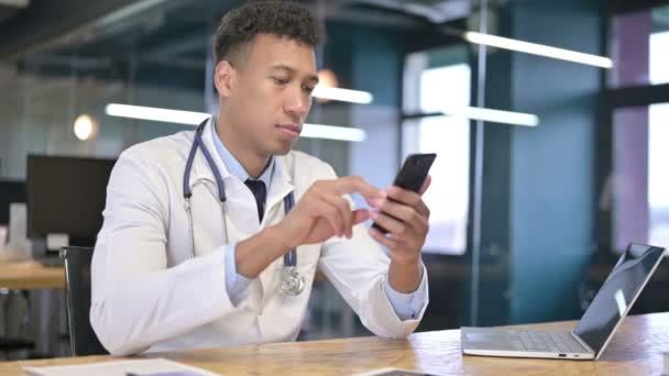 Привлекательный молодой врач с помощью смартфона в офисе — стоковое видео