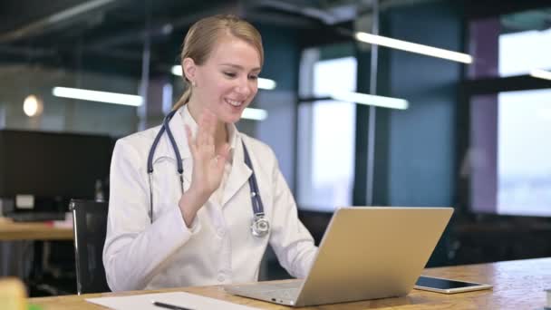 Jovem alegre médico feminino fazendo vídeo chat no laptop — Vídeo de Stock