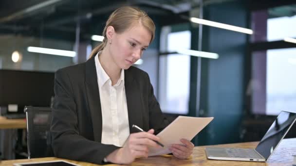 Трудолюбивая молодая предпринимательница читает документы в офисе — стоковое видео