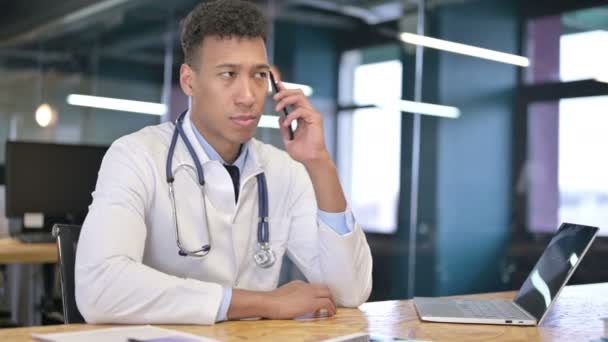 Glückliche junge Ärztin spricht im Büro mit Smartphone — Stockvideo
