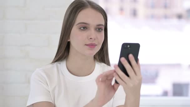 Retrato de una hermosa mujer joven celebrando el éxito en el teléfono inteligente — Vídeo de stock